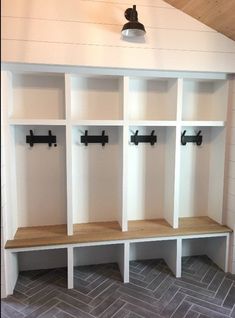 an empty room with white shelves and black hooks on the wall next to gray tile flooring