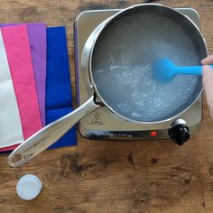 a person stirring water in a pot on top of a stove with a blue spatula