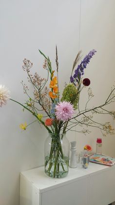 a vase filled with lots of flowers on top of a white table next to a mirror