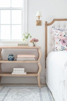 a bedroom with a white bed and pink flowers on the side table next to it