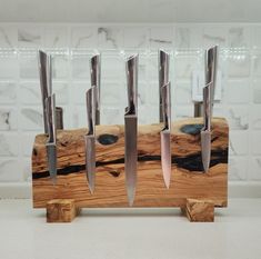 several knives are on a wooden stand with white tiles in the backgroung