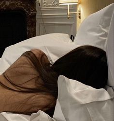 a woman is laying in bed with her head on the pillow and she has long dark hair