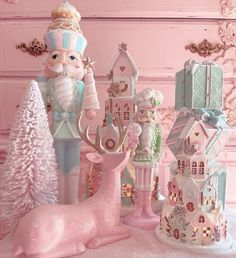 an assortment of christmas decorations and figurines on a pink tableclothed surface