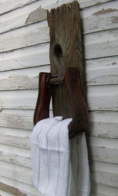 a pair of brown boots hanging from a hook on a wall next to a white towel