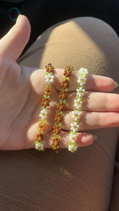 a woman's hand holding three beaded bracelets in the shape of flowers