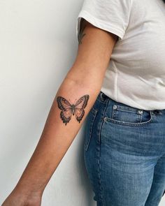 a woman's arm with a butterfly tattoo on the left side of her arm