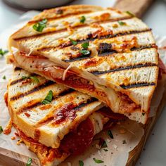 two grilled sandwiches sitting on top of a cutting board