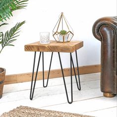 a wooden table sitting next to a brown leather chair and potted plant on top of it