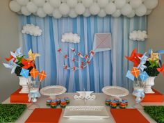 a table set up for a birthday party with balloons and paper airplanes on the wall