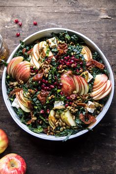 an apple and kale salad in a bowl on a wooden table next to apples