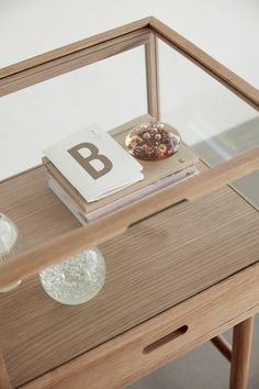 a wooden table topped with a glass shelf filled with books and an object on top of it