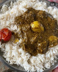 a plate filled with rice and some type of stew on top of it, next to a red pepper