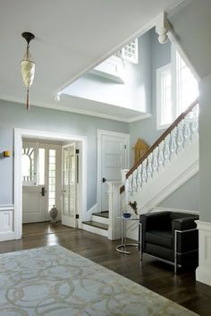 a living room filled with furniture next to a stair case and white railings on the wall