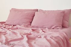 a bed with pink sheets and pillows on it