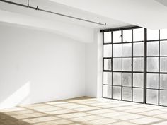 an empty room with large windows and wooden floors