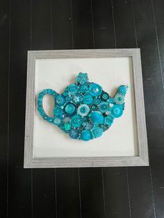 a teapot made out of buttons in a frame