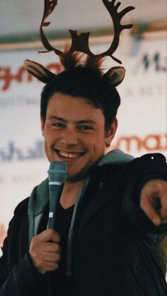 a man holding a microphone and wearing a deer's antlers on his head