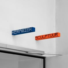 two blue and orange street signs mounted to the side of a building