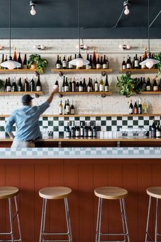 a man standing in front of a bar with lots of bottles on the wall behind him