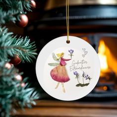 a christmas ornament hanging from a tree next to a fire place with flowers on it