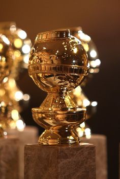 a golden trophy sitting on top of a marble block in front of some shiny lights