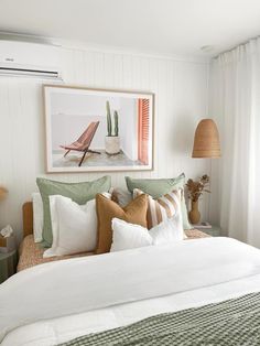 a bed with white sheets and green pillows