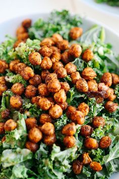 a white bowl filled with lettuce and chickpeas on top of a table