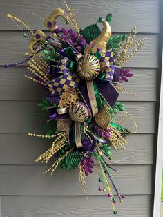 a purple and green wreath hanging on the side of a house