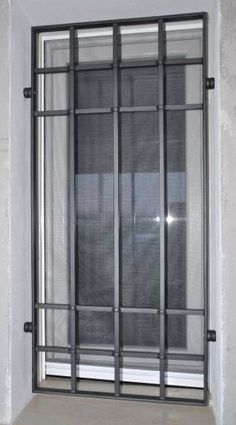 an open window with bars on the side of it in front of a white wall