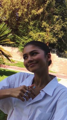 a woman is sitting in the grass with her hand on her hip and smiling at the camera