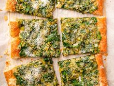 four square pieces of pizza with cheese and spinach on top, cut into squares