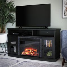 a living room with a fireplace and television on the stand in front of it, next to a blue chair