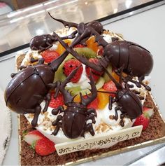 a cake decorated with chocolate bugs and strawberries