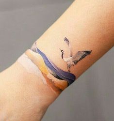 a small tattoo on the arm of a woman's hand with a bird flying over it