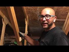 a man in glasses is working on some wooden beams and holding a screwdriver