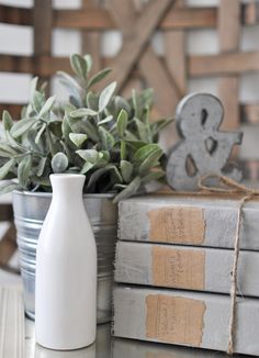 a white vase sitting on top of a table next to some books and a plant