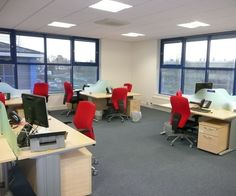 an empty office with red chairs and desks