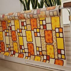 an orange and yellow curtain hanging from a window sill next to a potted plant