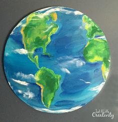 a painting of the earth is shown on a wall in front of a gray background