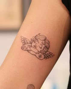 a tattoo on the arm of a woman with an angel and seashell in her hand