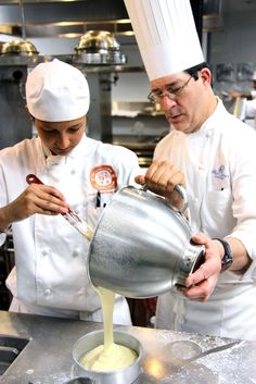 two chefs are in the kitchen making something yellow and white to stir them into sauce