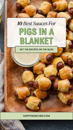 pigs in a blanket on a wooden cutting board with dipping sauce and napkins next to it