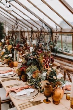 an image of a table setting with flowers and greenery on it for the autumn wedding