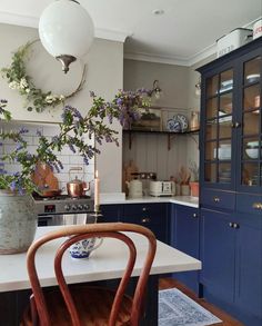 a kitchen with blue cabinets and purple flowers in vases on the counter top next to a wooden chair