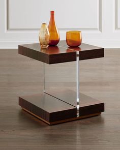 two vases sitting on top of a wooden table in front of a white wall