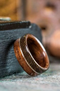 a wooden ring sitting on top of a black case next to a brown and white object