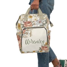 a woman carrying a white floral bag with the word wrenley on it's side