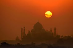 the sun is setting behind a large building