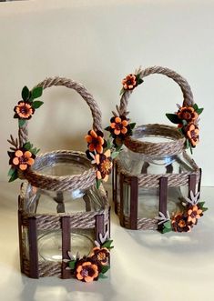 two glass baskets with flowers on them sitting on a table