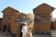 a man standing in front of a building made out of clay